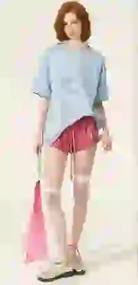 Modelka ma na sobie jasnoniebieski, oversize'owy t-shirt z okrągłym dekoltem i różowe szorty ze sznurkiem i falbaną u dołu. Szablon modelu zmieniacza ubrań AI.