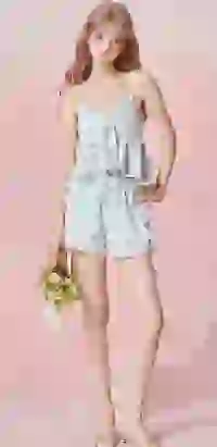 Modelka w jasnoniebieskiej koszulce na ramiączkach z falbanami w kratkę i z nadrukiem wiśni oraz szortach z elastyczną talią, pozuje z bukietem kwiatów. Szablon modelu zmieniacza ubrań AI.