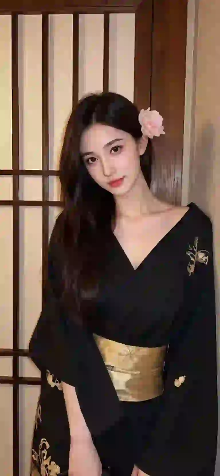 Mujer asiática con kimono negro posando en una habitación de estilo japonés.