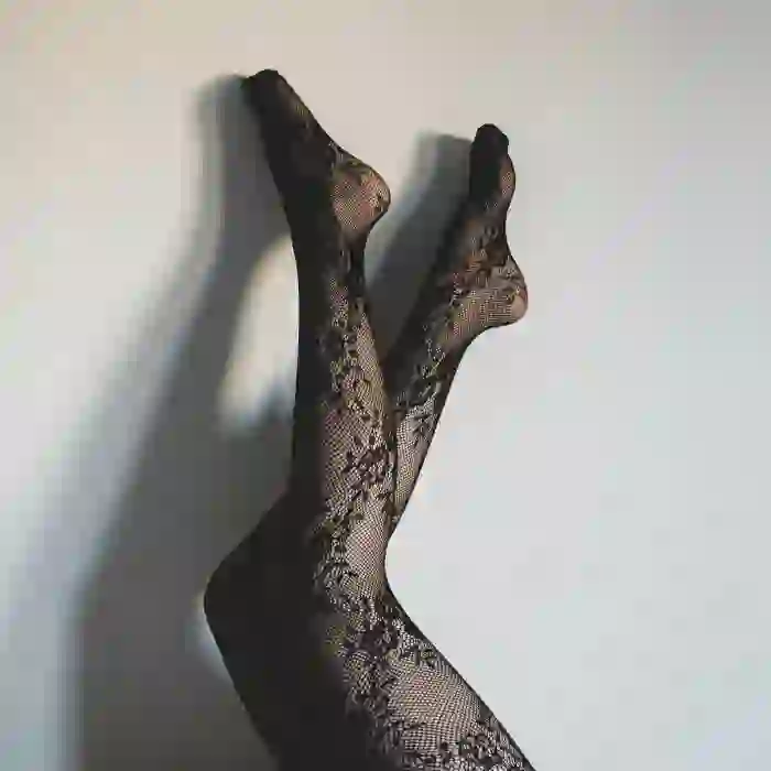 Photo of a pair of legs wearing black lace-patterned sheer tights.
