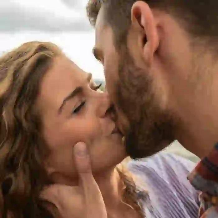 Close-up of a couple kissing affectionately, with the man's hand gently cupping the woman's neck.