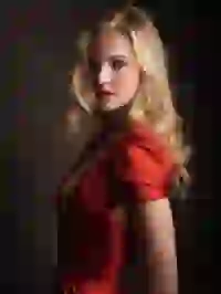 Side-view of a blonde woman in red dress with deep V-neck. Template for Undress AI.