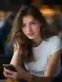 Portrait of a smiling blonde woman sitting ceside a desk with a phone in her hand. Template for Undress AI.