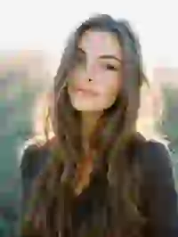 Portraif of a smiling blonde woman in black long sleeve top standing in the sunlight. Template for Undress AI.